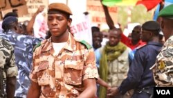 A national guard soldier walks by demonstrators at Bamako airport, Mali, March 29, 2012. (VOA - N. Palus)