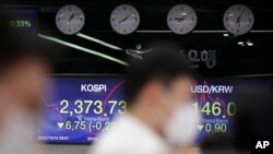 Currency traders watch computer monitors near screens showing the Korea Composite Stock Price Index and the foreign exchange rate between U.S. dollar and South Korean won in Seoul, South Korea, Oct. 15, 2020.