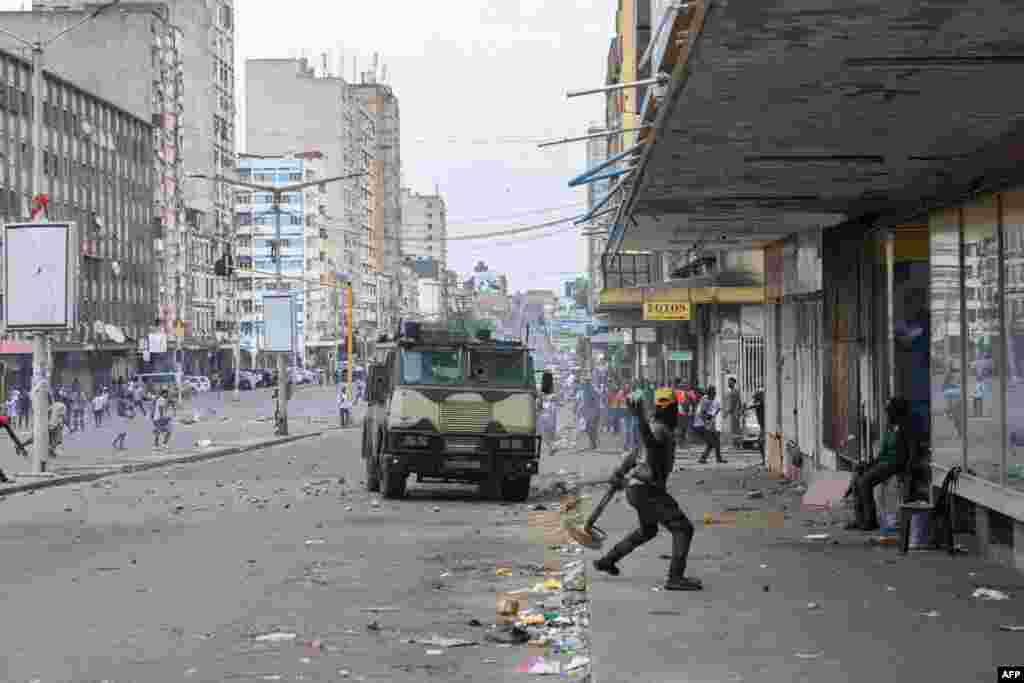 Um manifestante atira uma pedra contra um veículo blindado enquanto os manifestantes entram em confronto com a polícia de choque moçambicana em Maputo, em 27 de novembro