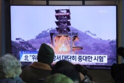 People watch a TV screen showing a file image of a ground test of North Korea's rocket engine during a news program at the Seoul Railway Station in Seoul, South Korea, Dec. 9, 2019.
