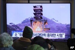People watch a TV screen showing a file image of a ground test of North Korea's rocket engine during a news program at the Seoul Railway Station in Seoul, South Korea, Dec. 9, 2019.