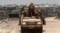 Kenya Defence Force (KDF) soldiers, serving in the African Union Mission in Somalia (AMISOM), patrol past stockpiles of charcoal near the Kismayo sea port town in lower Juba region, Somalia, Feb. 27, 2013.