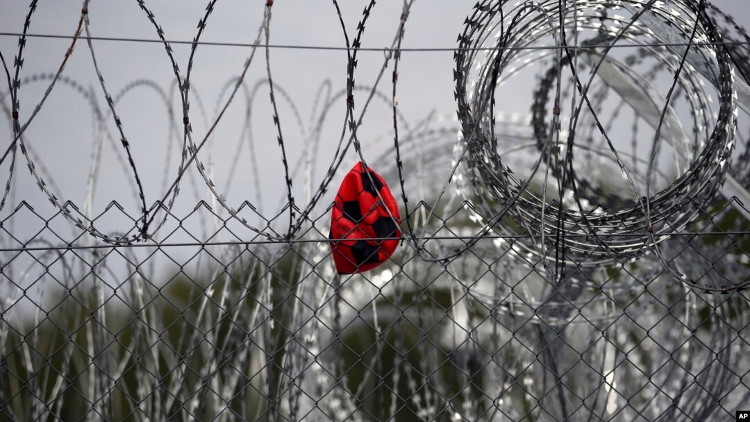 FILE - A punctured ball hangs on barbed wire in the heavily guarded camp at Serbia's border with Hungary, near the Horgos border crossing, Serbia, Sept. 19, 2017.