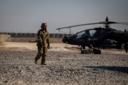 A crewman walks past an attack helicopter at a U.S. military base at an undisclosed location in eastern Syria, Nov. 11, 2019.