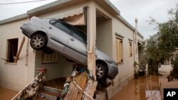 A car rests at the entrance of a flooded house after the water has receded in the town of Mandra, Greece, Nov. 16, 2017.