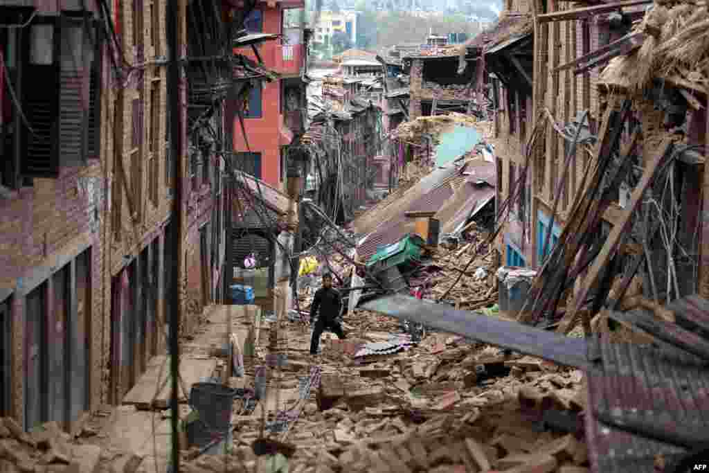 A man walks through the damage of houses damaged by the earthquake in Bhaktapur near Kathmandu, Nepal. Hungry and desperate villagers rushed towards relief helicopters in remote areas Tuesday, begging to be airlifted to safety, four days after an earthquake killed nearly 4,500 people.