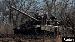 ডনেৎস্ক অঞ্চলে ইউক্রেনের সেনা সদস্যরা ফ্রন্টলাইন শহর বাখমুতের বাইরে একটি ট্যাঙ্কের উপর বসে। ( ৪ মার্চ, ২০২৩)