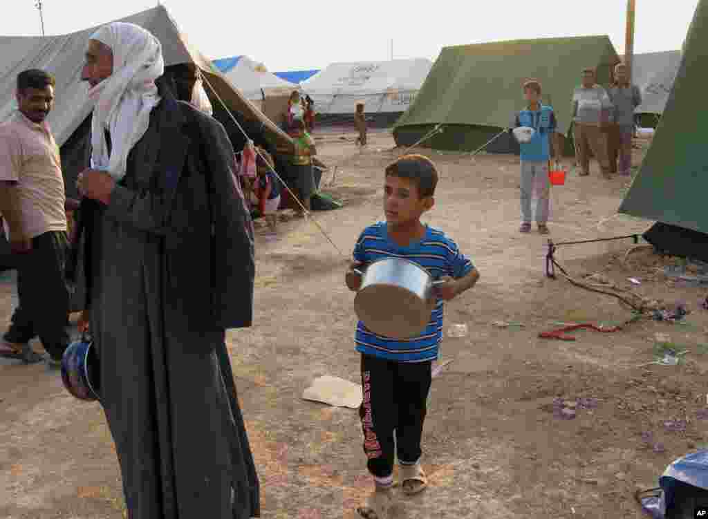 Iraqis who fled from Baqouba and other towns after advances by Islamic militants wait for food distribution at a camp in Khanaqin, northeast of Baghdad, July 6, 2014. 