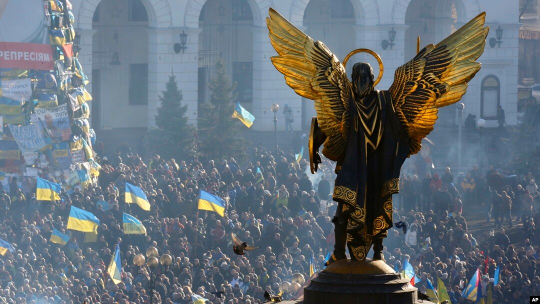 The Archangel Michael statue towers over pro-European Union activists during a rally in Independence Square in Kyiv, Ukraine, Saturday, Dec. 14, 2013.