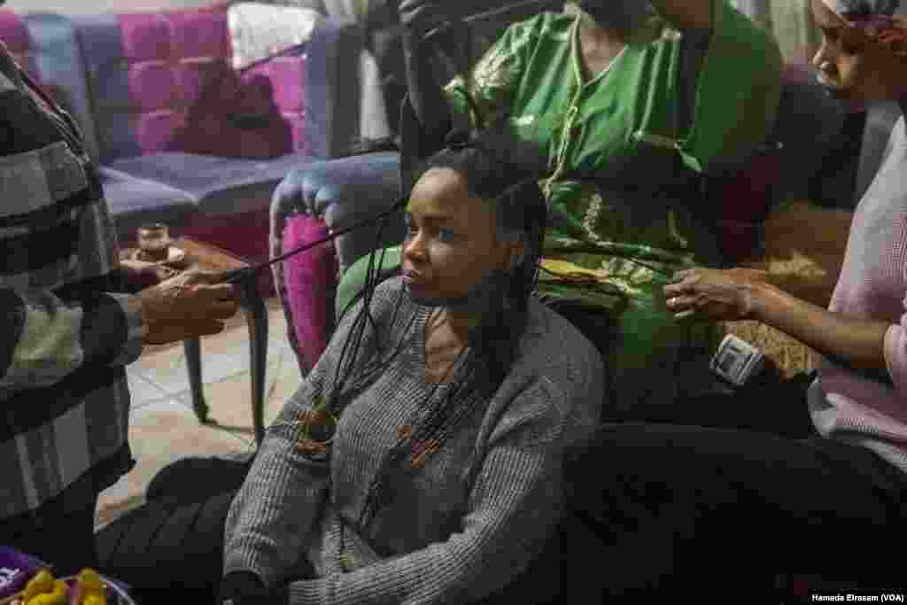 Mona, a Sudanese English teacher, has her hair braided by her fellow displaced countrywomen in Cairo on Dec. 17, 2024. &ldquo;We leave Sudan, but Sudan does not leave us,&rdquo; she said.