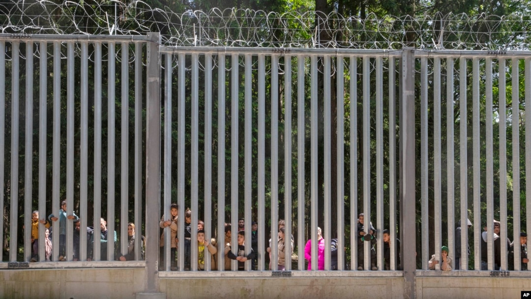 Members of a group of some 30 migrants seeking asylum are seen in Bialowieza, Poland, on May 28, 2023 across a wall that Poland has built on its border with Belarus to stop massive migrant pressure.