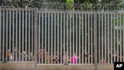 Members of a group of some 30 migrants seeking asylum are seen in Bialowieza, Poland, on May 28, 2023 across a wall that Poland has built on its border with Belarus to stop massive migrant pressure.