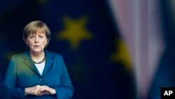 Kanselir Jerman Angela Merkel berdiri di belakang jendela dengan pantulan bendera Eropa saat dia menunggu kedatangan Raja Willem-Alexander dari Belanda di kanselir di Berlin. (Foto: AP/Markus S)