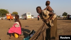 A refugee mother from South Sudan prepares to carry her child on her back on arrival at Bidi Bidi refugee’s resettlement camp near the border with South Sudan, in Yumbe district, northern Uganda, Dec. 7, 2016. 