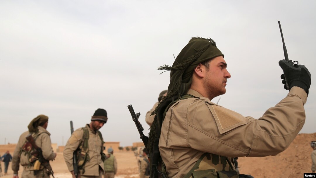 FILE - A Syrian Democratic Forces (SDF) fighter carries a walkie talkie as he stands with his fellow fighters during an offensive against Islamic State militants in northern Raqqa province, Syria February 8, 2017.