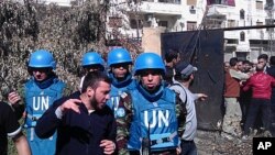 A handout picture released by the Syrian opposition's Shaam News Network shows Syrian residents talking to Moroccan UN observer, Colonel Ahmed Himmiche (R) during the monitors' visit to the Khalidiya district in the restive city of Homs, April 21, 2012. 