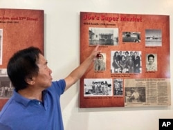 Allen Lew points to a display board at the Tucson Chinese Cultural Center in Tucson, Arizona, on Sunday, Oct. 16, 2022 highlighting his father's grocery store business. (AP Photo/Terry Tang)