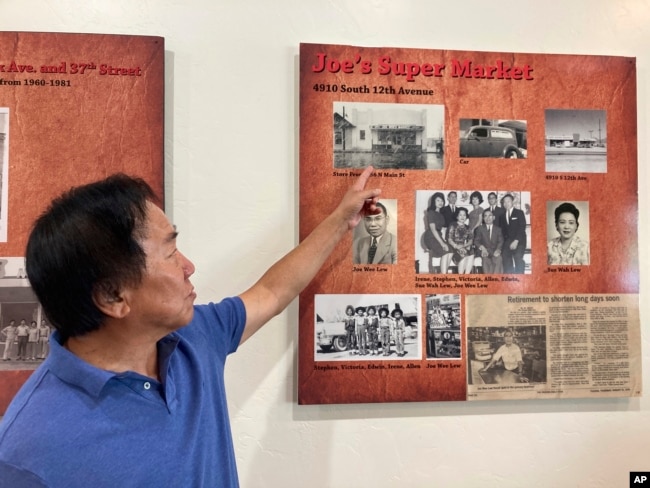 Allen Lew points to a display board at the Tucson Chinese Cultural Center in Tucson, Arizona, on Sunday, Oct. 16, 2022 highlighting his father's grocery store business. (AP Photo/Terry Tang)