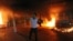 An armed man waves his rifle as buildings and cars are engulfed in flames after being set on fire inside the US consulate compound in Benghazi late on September 11, 2012. 