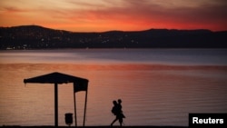 FILE - A man walks on the shore of the Sea of Galilee during sunset near the northern city of Tiberias.