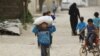 FILE - A boy carries food aid given by UN's World Food Program in Raqqa, Syria, April 26, 2018. 