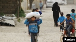 FILE - A boy carries food aid given by UN's World Food Program in Raqqa, Syria, April 26, 2018. 