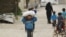 FILE - A boy carries food aid given by UN's World Food Program in Raqqa, Syria, April 26, 2018. 