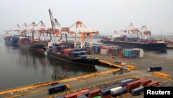 FILE - Cargo vessels wait to unload containers, while docked at the port in Manila, Aug. 20, 2014. 