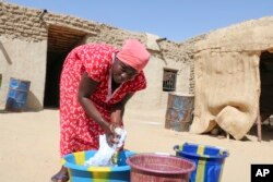 FILE - Zahra Abdou washes laundry in Timbuktu, Mali, Wednesday. Sept. 29, 2021. It's been nine years since Islamic extremists in northern Mali arrested Abdou on charges of showing her hair and wearing an outfit they said was too tight.