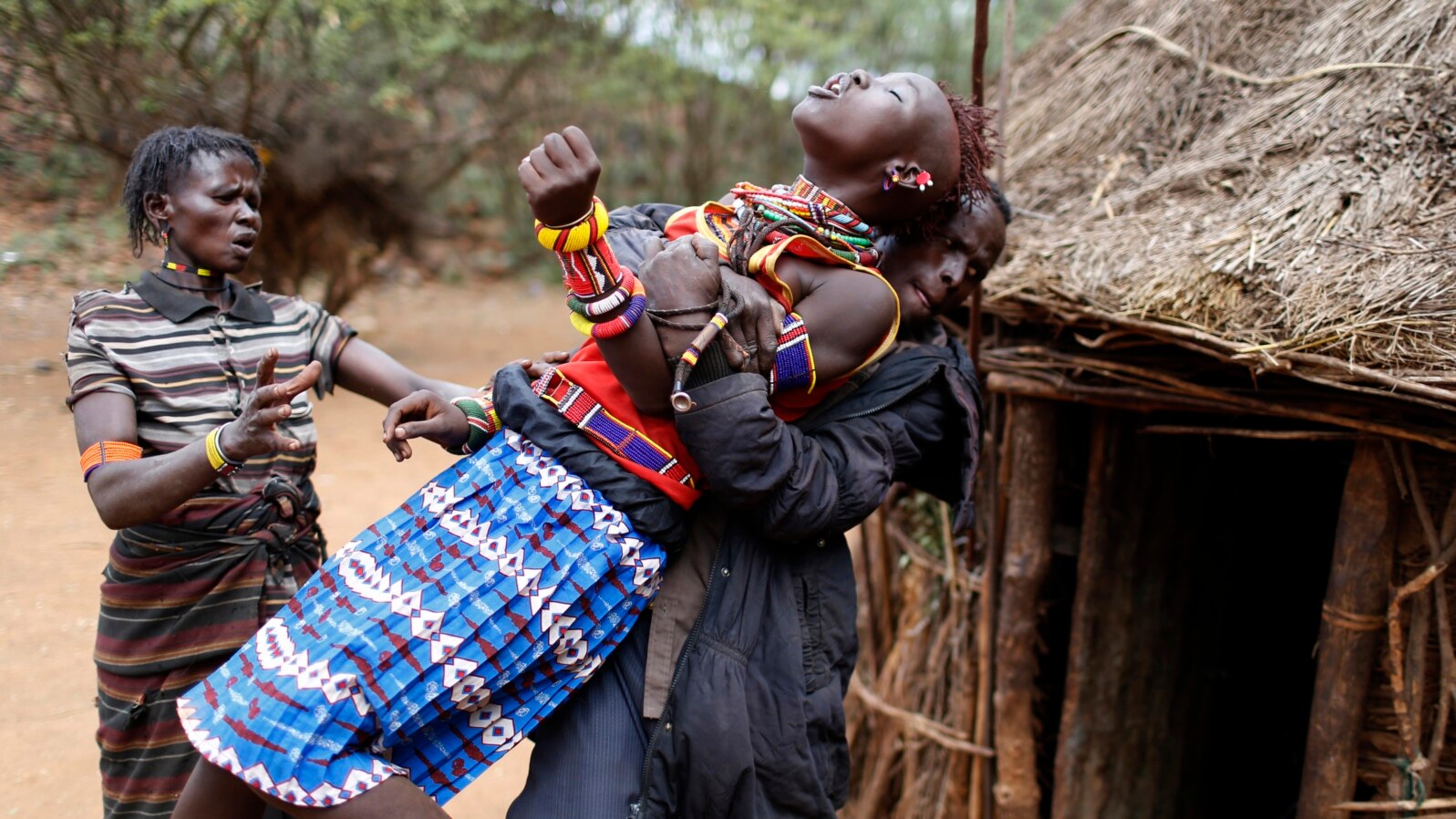 FILE - A man holds a girl as she tries to escape when she realized she is to to be married, about 80 km (50 miles) from the town of Marigat in Baringo County, Dec. 7, 2014.