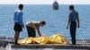 FILE - Crew members inspect bags containing bodies believed to be victims of AirAsia Flight 8501 on the deck of Indonesian Navy ship KRI Banda Aceh, on the Java Sea, Indonesia, Friday, Jan. 23, 2015.