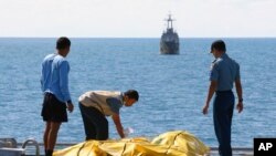 Beberapa anggota Basarnas memeriksa jenazah penumpang korban pesawat AirAsia di atas kapal Angkatan Laut KRI Banda Aceh di Laut Jawa (23/1). (AP/Natanael Pohan)