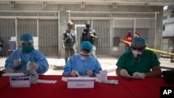 Trabajadores de la Salud hacen pruebas de coronavirus en un mercado de Caracas. El gobierno en disputa asegura haber realizado un millón de pruebas. Pero la Organización Mundial de la Salud calcula que fueron unas 1.800.