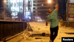 A supporter of deposed Egyptian President Mohamed Morsi throws stones at riot police during clashes in the Ramsis square area in central Cairo, July 15, 2013. 