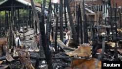 A man walks through a neighborhood that was burnt in recent violence in Sittwe, June 16, 2012.