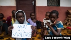 Une jeune musulmane déplacée brandit un écriteau mentionnant “Non à la violence“ dans un centre installé dans une église catholique à Bangassou, Centrafrique, 17 juillet 2017.