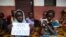 FILE - A young displaced Muslim girl holds a sign saying “No to Violence” at a displaced persons site, the Catholic church in Bangassou, Central African Republic.