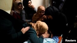 The mother of Palestinian Mosab al-Tamimi, who was killed during clashes with Israeli troops, kisses his body at a hospital in the West Bank city of Ramallah, Jan. 3, 2018. 