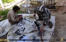 FILE - In this photo released June 16, 2015, by Islamic State militant group supporters on an anonymous photo-sharing website, IS militants clean their weapons in Deir el-Zour city, Syria.