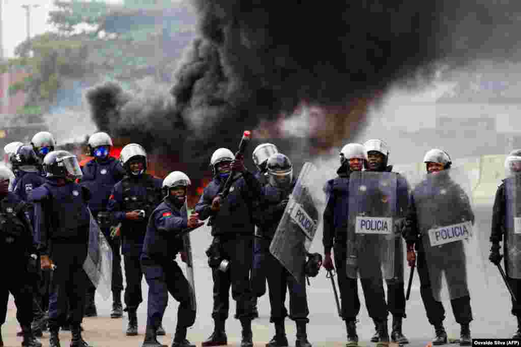 Um pol&#237;cia prepara-se para atirar g&#225;s lacrimog&#233;neo durante uma manifesta&#231;&#227;o anti-governo. A pol&#237;cia anti-motim, alguns montados em cavalos, disparou g&#225;s lacrimog&#233;neo e agrediu dezenas de manifestantes que tomaram as ruas da capital angolana. 24 outubro 20
