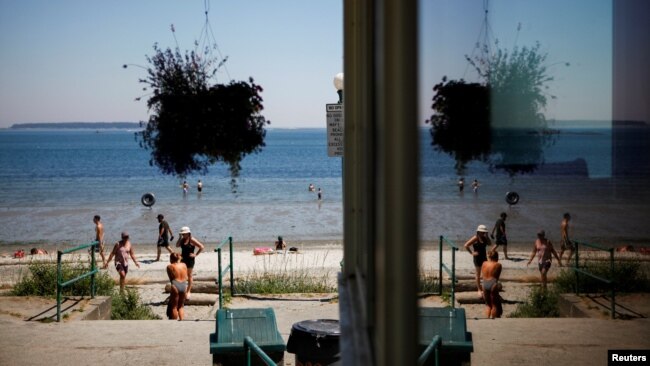 FILE - People look for ways to cool off at Willow's Beach during the "heat dome," that hovered over British Columbia and Alberta amid record-setting temperatures in Victoria, British Columbia, June 28, 2021.