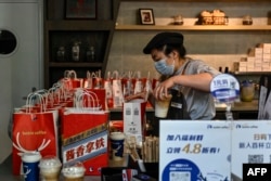 FILE - Seorang karyawan Luckin Coffee menyiapkan latte rasa minuman keras baijiu, produk terbaru hasil kerja sama dengan merek minuman keras China Kweichow Moutai, di kedai Luckin Coffee di Beijing pada 4 September 2023.(Jade GAO / AFP)