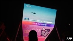 FILE - A man watches a news program about Chinese military drills surrounding Taiwan, on a giant screen outside a shopping mall in Beijing on October 14, 2024.