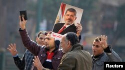 FILE - Supporters of the Muslim Brotherhood and ousted Egyptian President Mohammed Morsi hold a copy of the Koran and Morsi's picture at Talaat Harb Square, in Cairo, Jan. 25, 2015. 