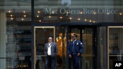 Two Lincoln Center security officials walk in front of the Metropolitan Opera box office Thursday, March 12, 2020, in New York after New York Gov. Andrew Cuomo temporarily banned gatherings of more than 500 people. 