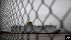 Una vista a través de una valla de un barco de pasajeros que permanece atracado en un muelle en el puerto de El Pireo, cerca de Atenas, el sábado 4 de abril de 2020.