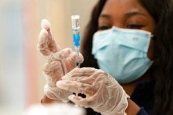 FILE - A health worker loads syringes with the vaccine on the first day of the Johnson & Johnson vaccine being made available to residents at the Baldwin Hills Crenshaw Plaza in Los Angeles. California, March 11, 2021.