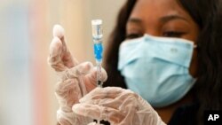 FILE - A health worker loads syringes with the vaccine on the first day of the Johnson & Johnson vaccine being made available to residents at the Baldwin Hills Crenshaw Plaza in Los Angeles. California, March 11, 2021.