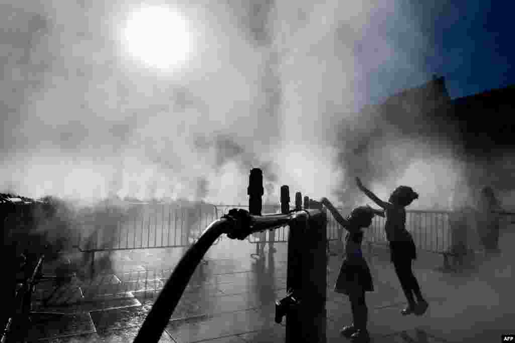 Children play next to a water atomizer on a central square in Strasbourg, eastern France.