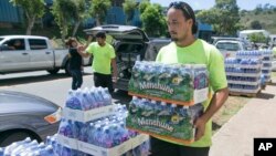 FILE - A worker at the Hawaiian water company carries bottle of water to customers hoping to stockpile water before a 2014 tropical storm.